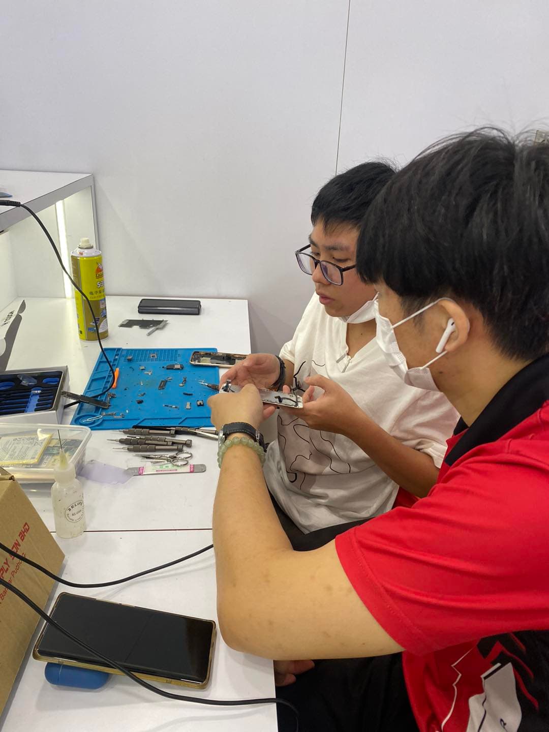 Coach guiding a student through phone disassembly